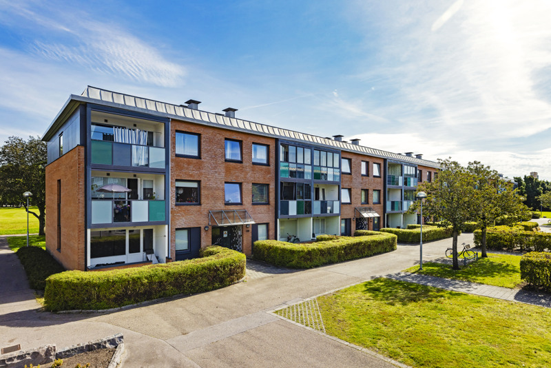 En byggnad med många fönster och buskar framför den.