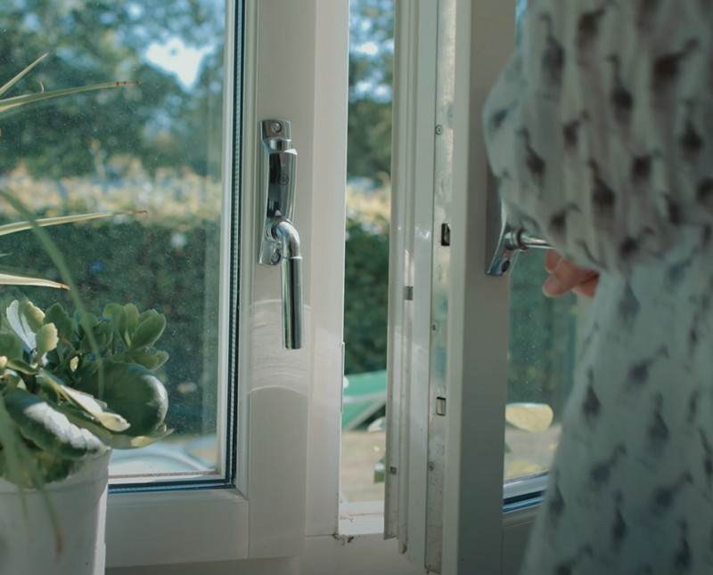 En person öppnar ett fönster på glänt för att vädra.