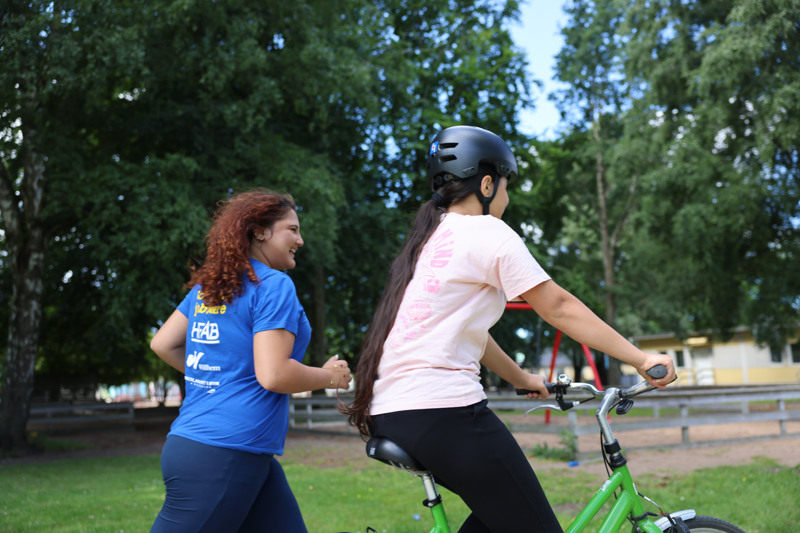 En tjej springer medan den andra cyklar.