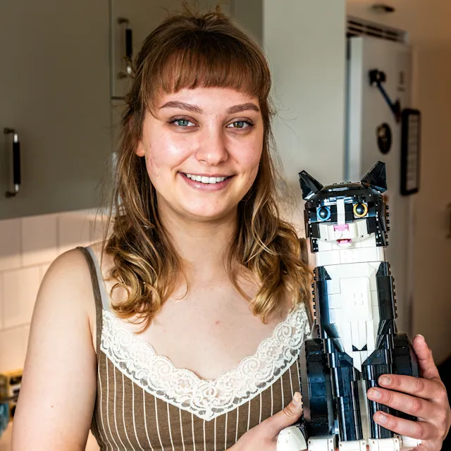 En kvinna som håller i en katt gjord av lego.
