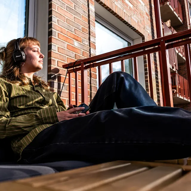 En man sitter på en soffa och lyssnar på musik.