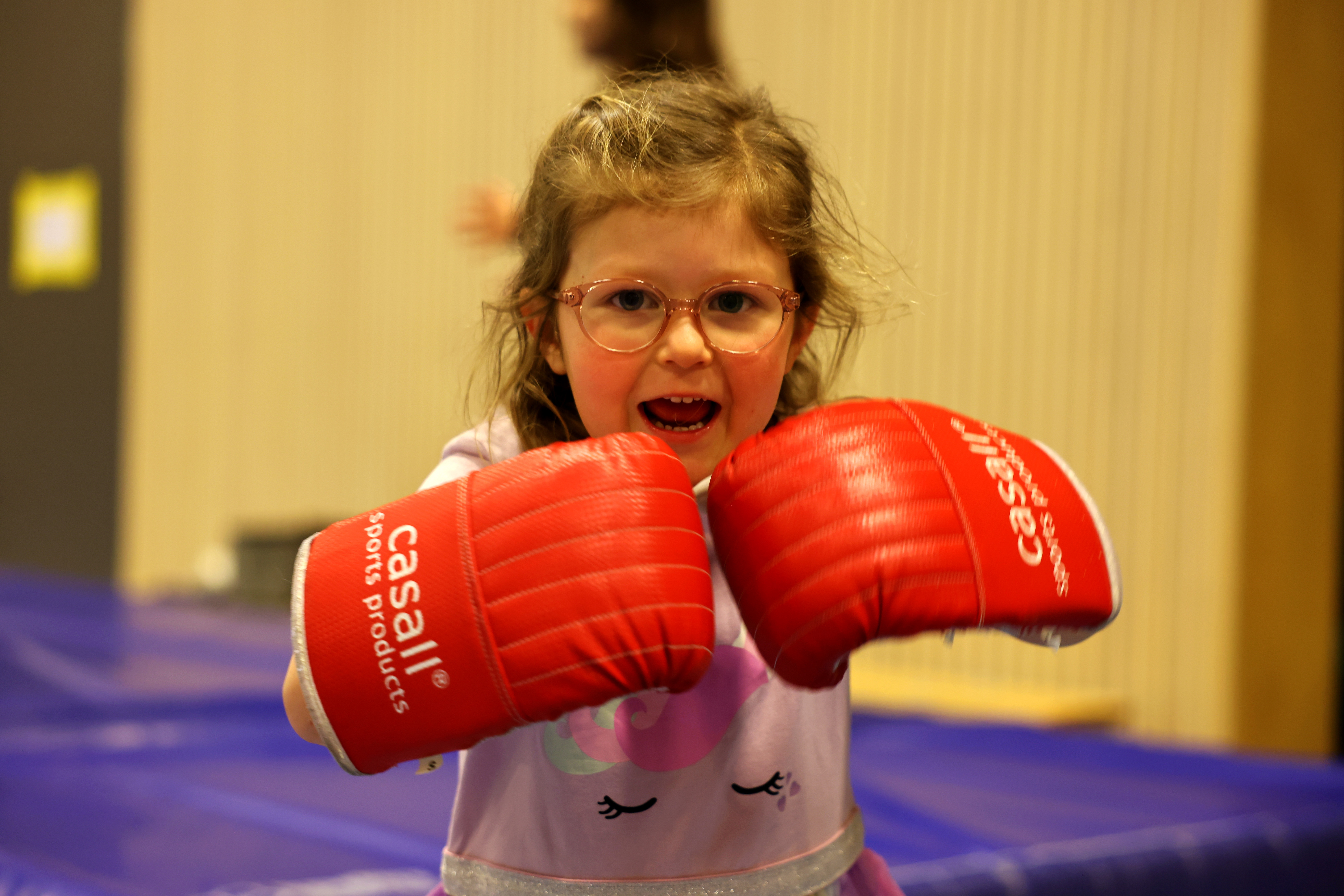 En liten flicka med röda boxningshandskar på sig.