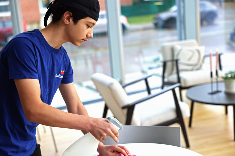 En man i blå skjorta diskar ett bord.