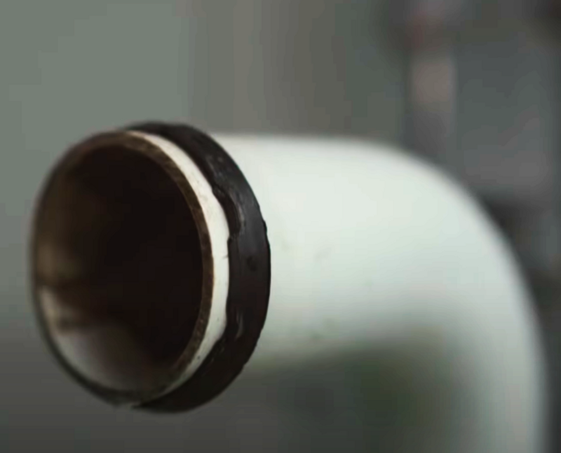 Packning, en svart gummilist, på ett rör under handfatet.