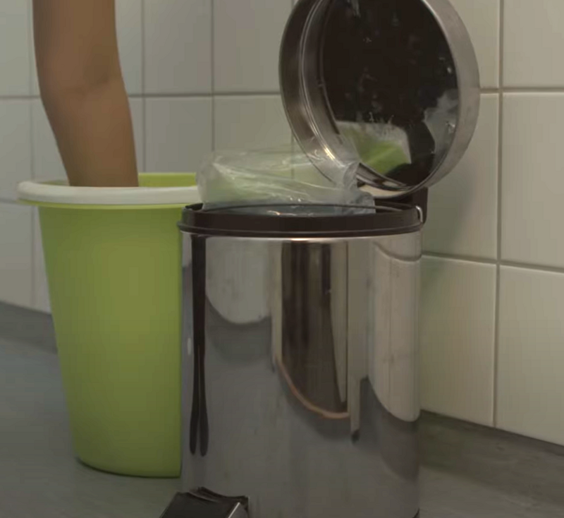 Grön hink bredvid en soptunna i metall.