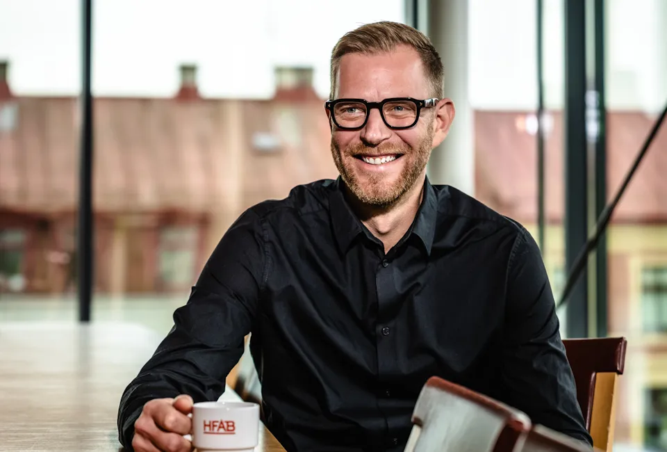 En man sitter vid ett bord med en kopp kaffe.