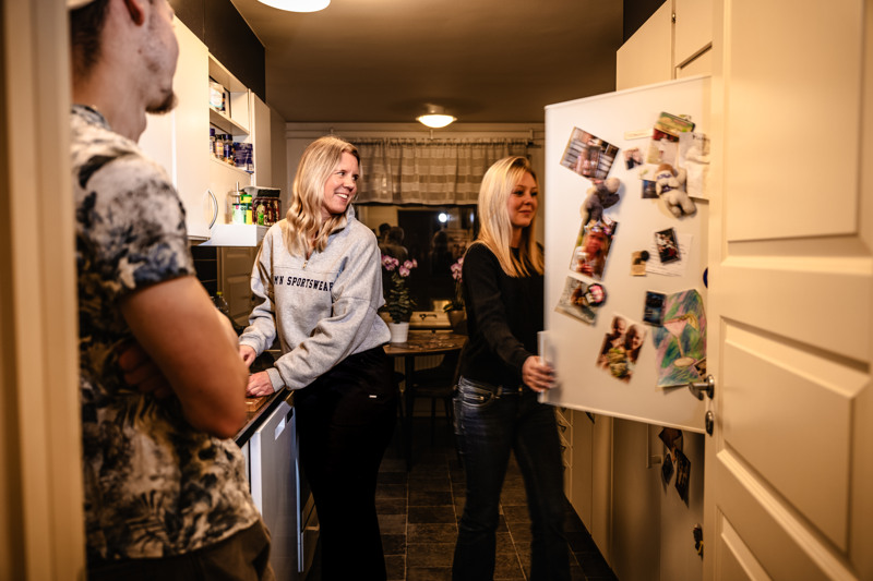 Några kvinnor som står i ett kök bredvid ett kylskåp.