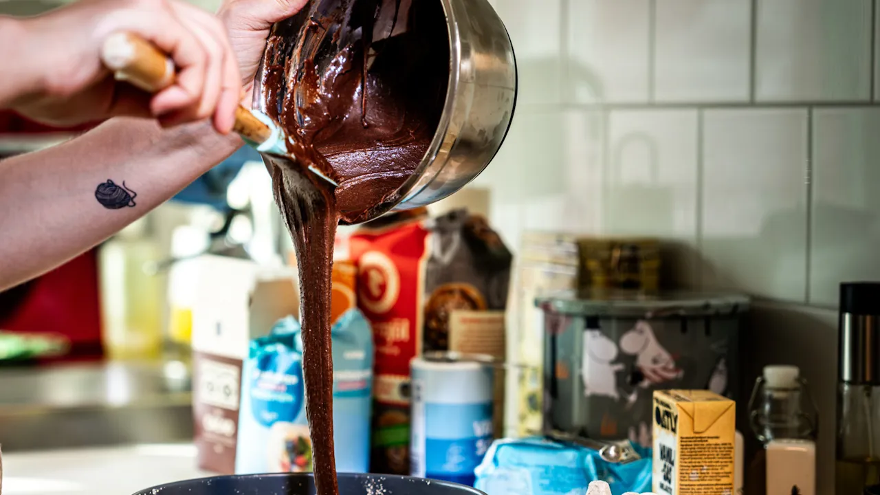 En person som häller chokladsmet i en springform.