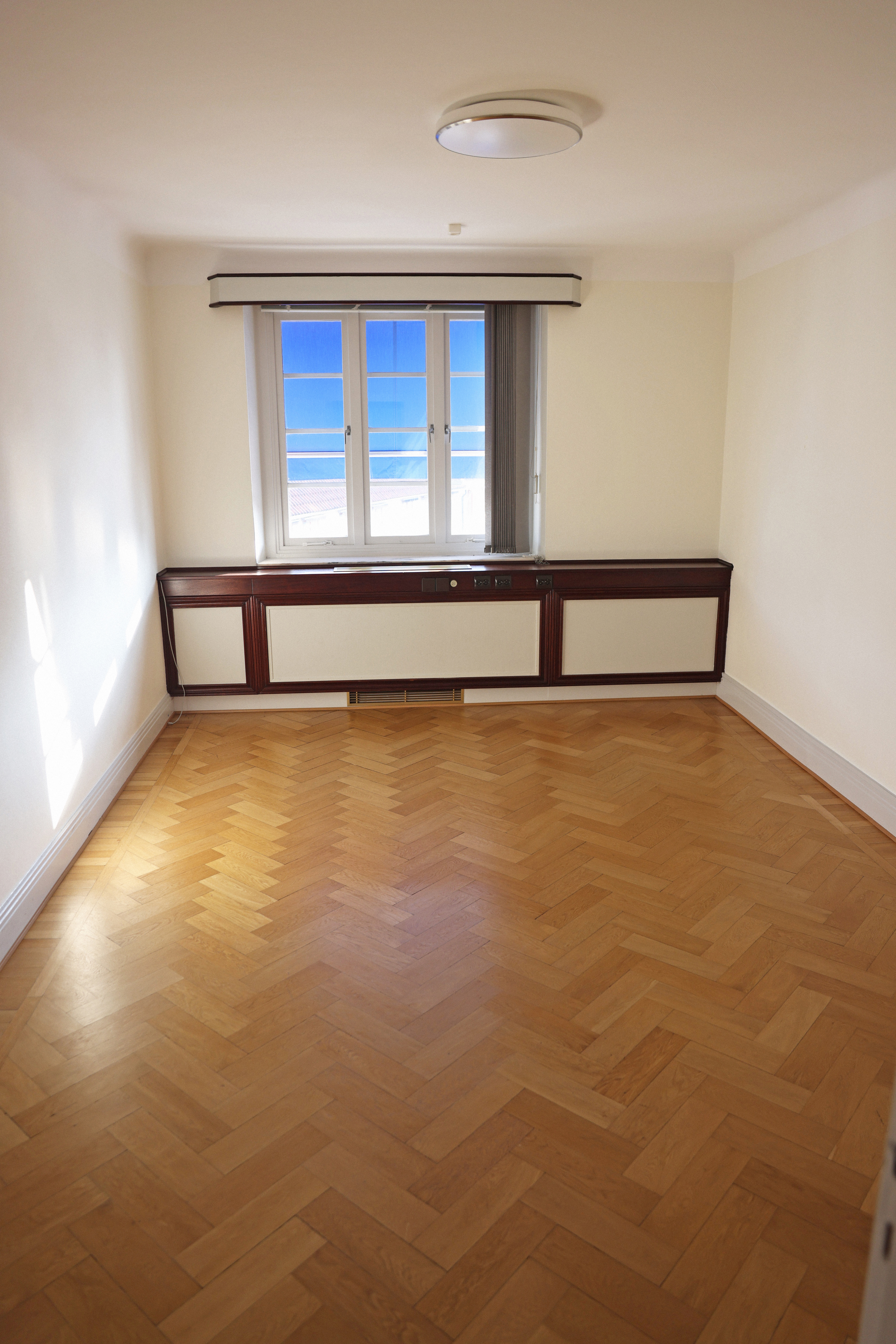 Ett tomt rum med trägolv och ett fönster.