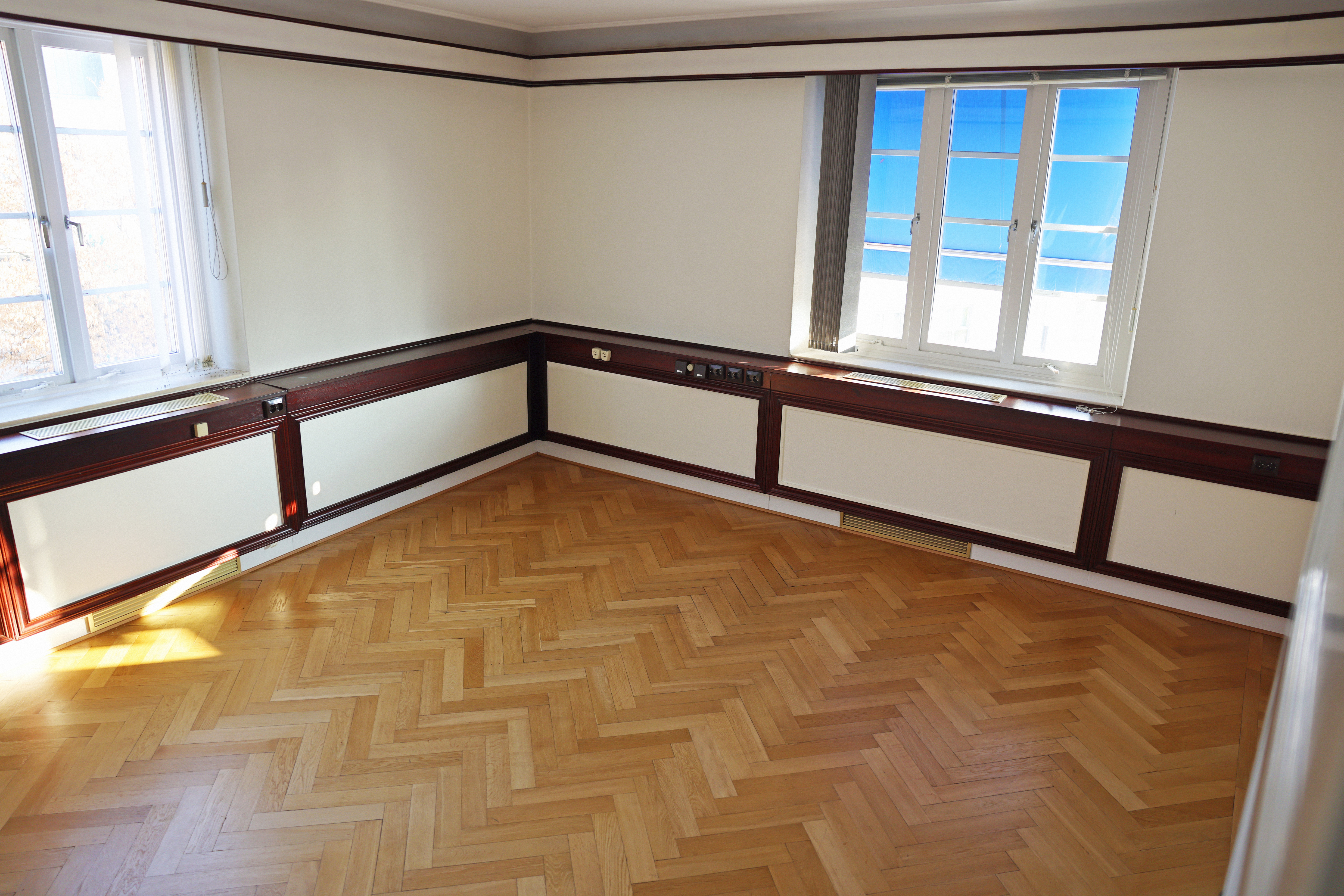 Ett tomt rum med trägolv och fönster.